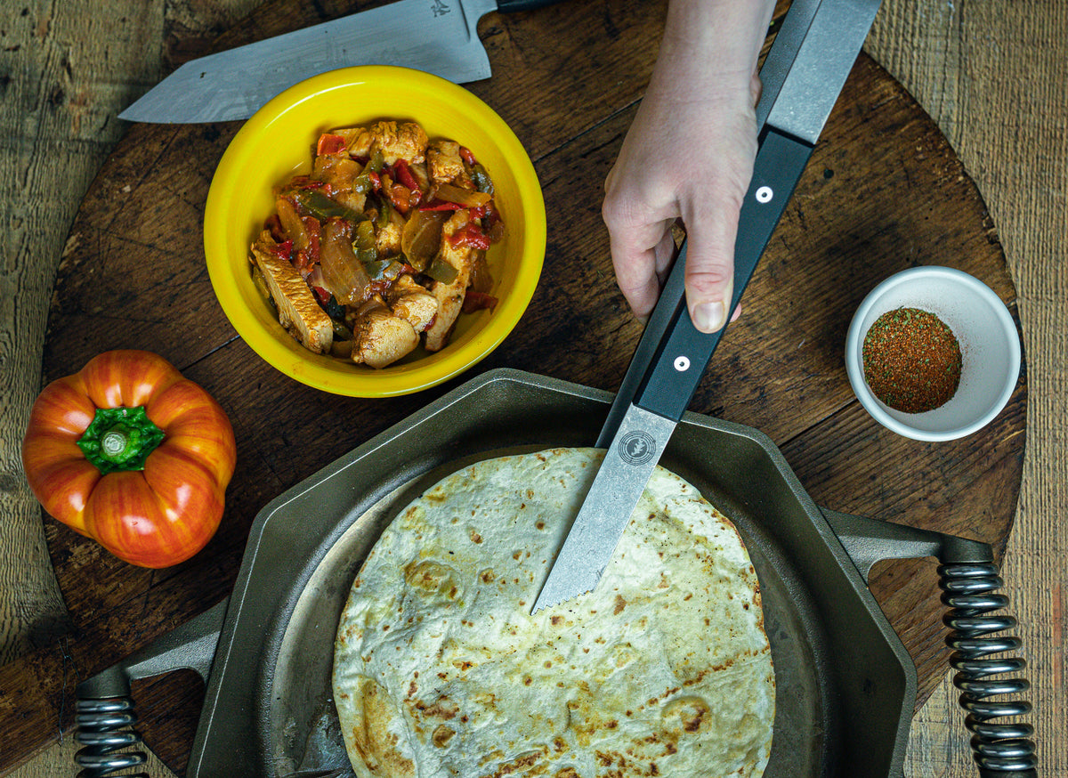 a black handled titanium tong picking up a tortilla